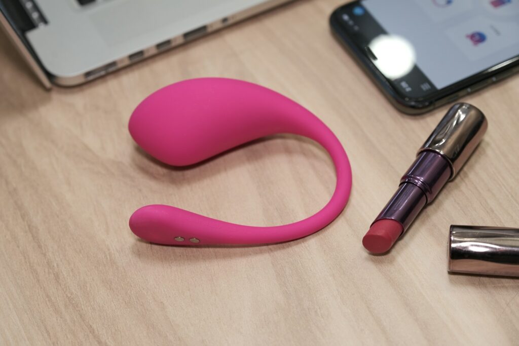 a table with a cell phone, lipstick, and a laptop